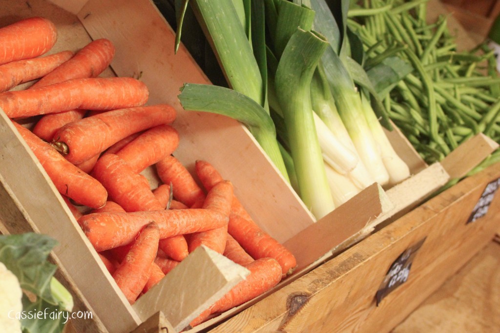 Farm shop produce on shelves, including carrots, leeks and beans