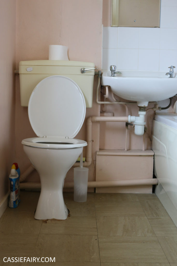 'Before' photo of an old toilet and sink with a muddle of pipework underneath