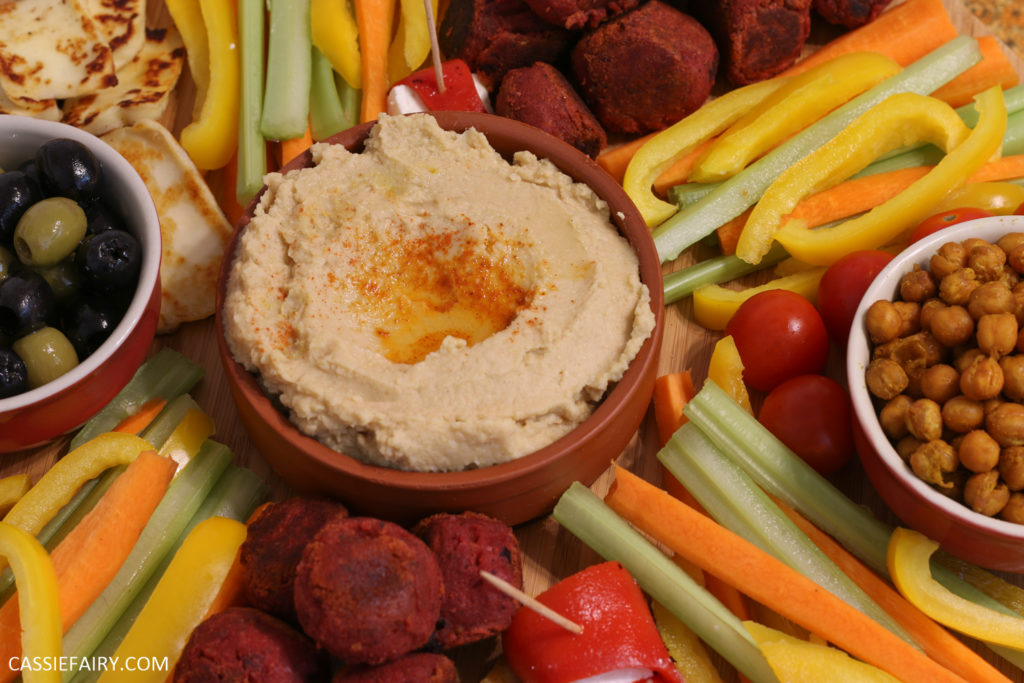 A platter of vegetable crudities arranged around a bowl of hummus. 