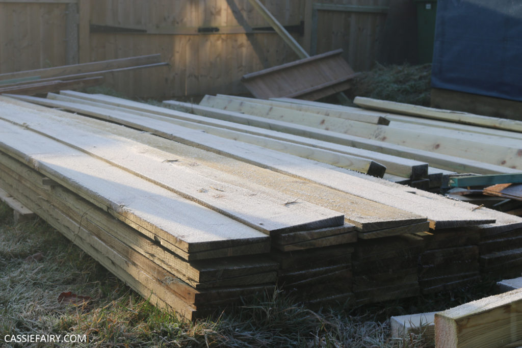 Pile of wood planks in garden, covered in frost.