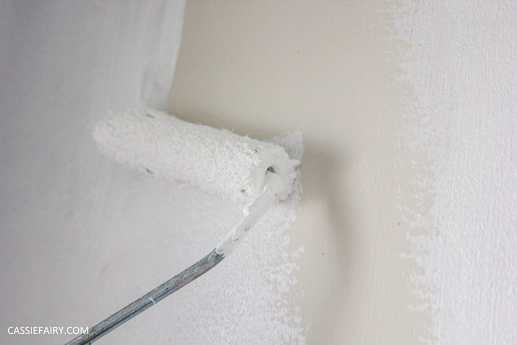 white paint being rolled onto a wall 