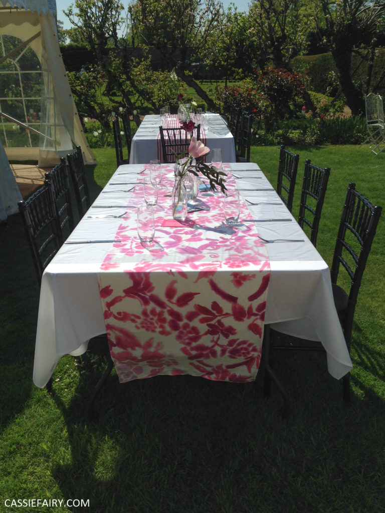 outdoor wedding reception with pink tablecloth and flowers in jam jars