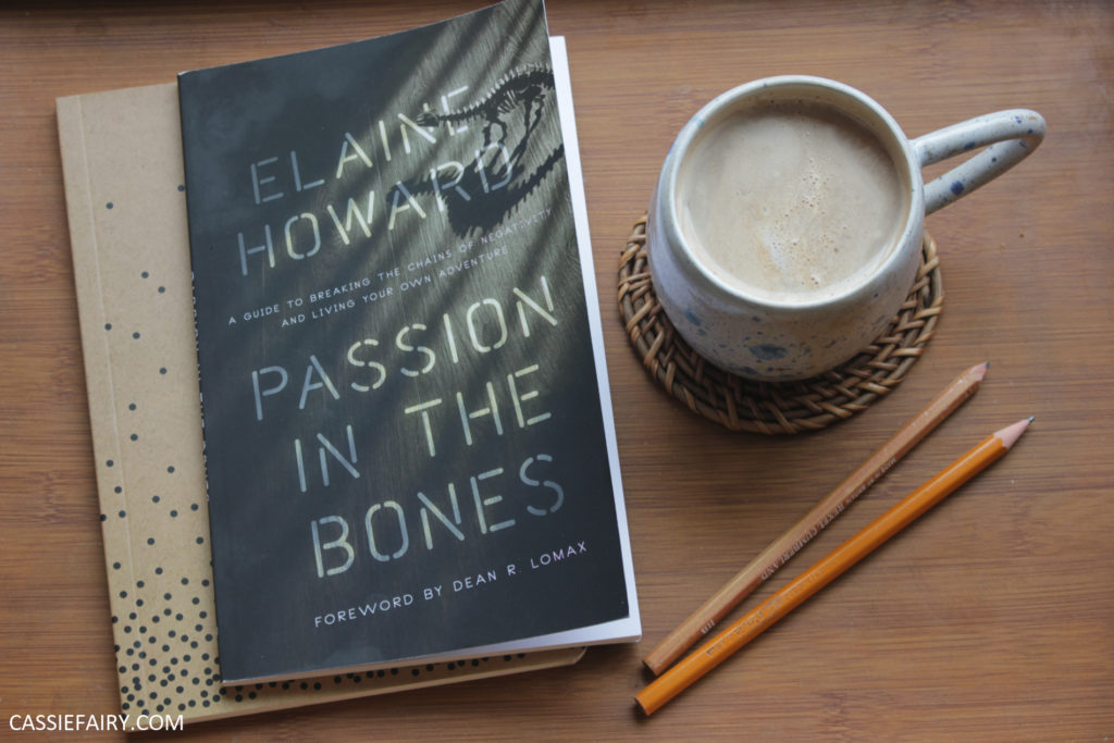 Passion in the Bones book by Elaine Howard alongside a notebook and mug of coffee