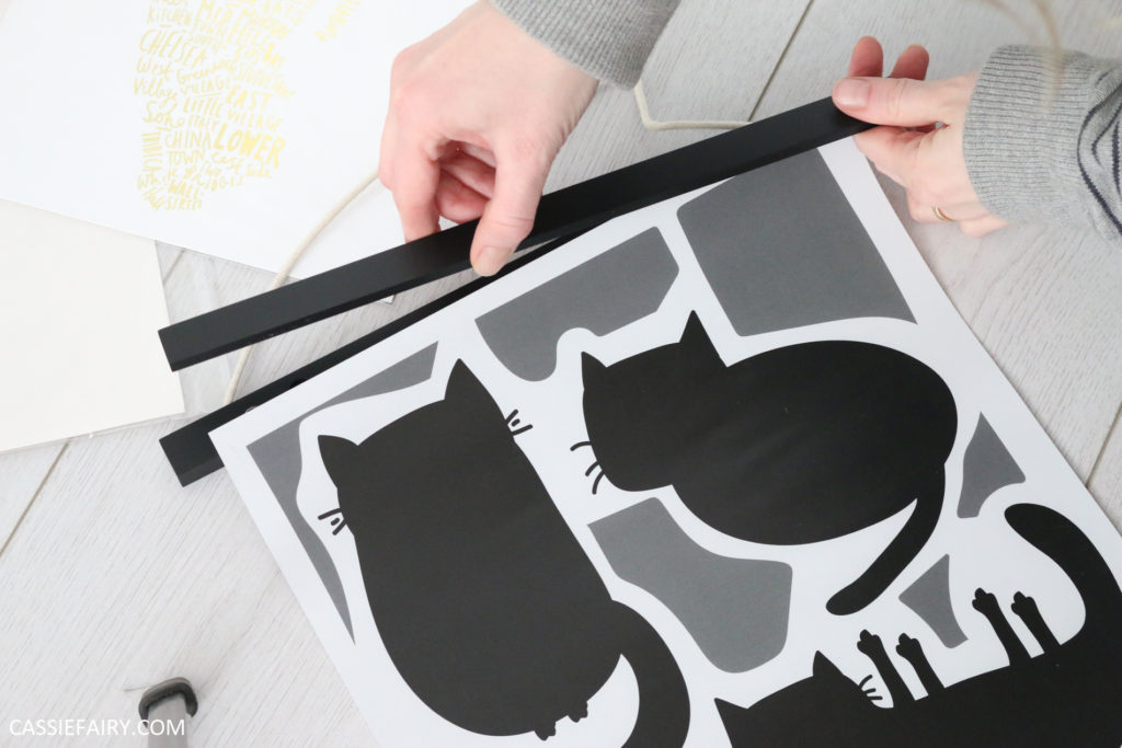 magnetic hanging frame being applied to a poster print of black and white cats