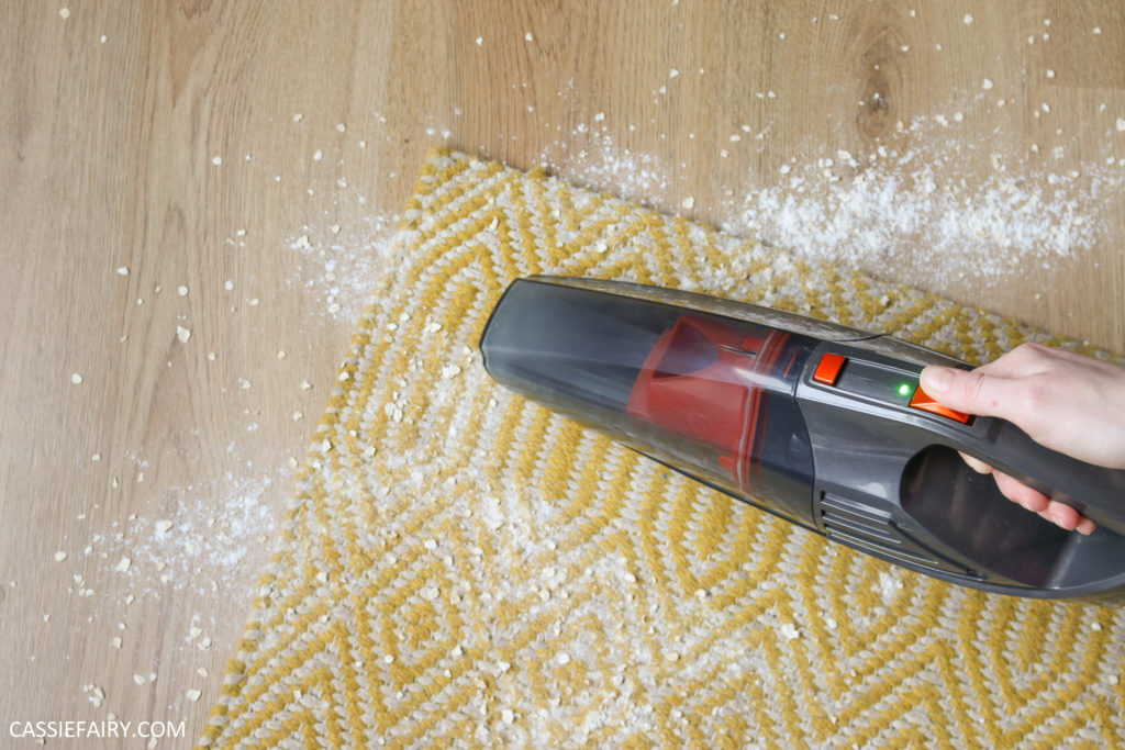 photo of handheld vacuum sucking up spilled flour off a yellow rug