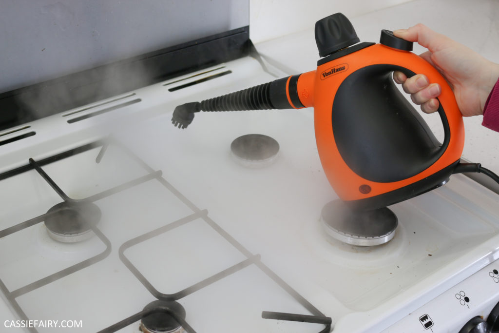 Photo of handheld steam cleaner scrubbing a hob with steam.