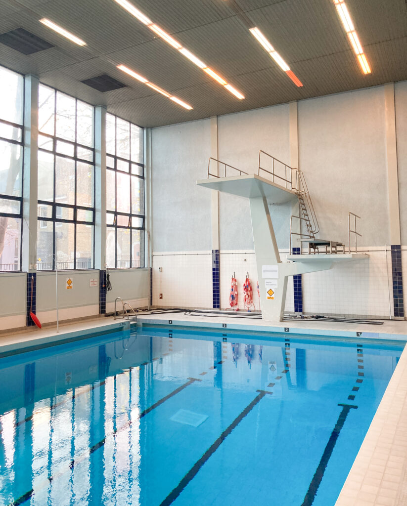 A blue swimming pool with a diving board over it.