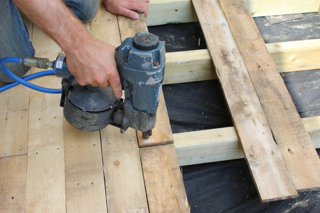 A nail-gun nailing the pallet planks into the frame.