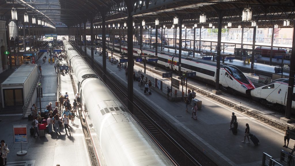 An image of the interior of a railway station taken from a bridge, showing the platforms with multiple trains and people boarding them.
