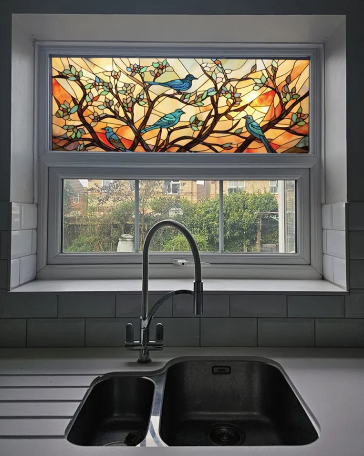 A stained glass effect window film depicting birds on branches on a window above a sink, created by Signs For You.