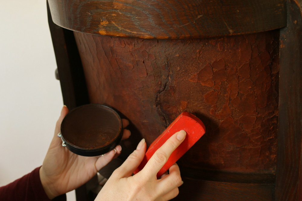 Brown leather polish being applied to the repaired crack using a boot brush.