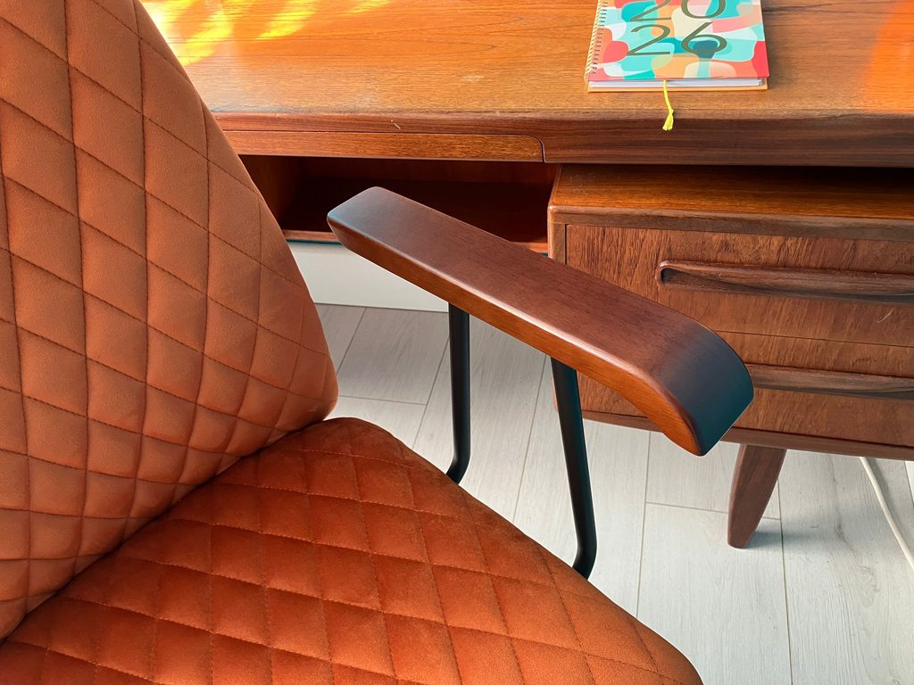A teak G-Plan desk and a padded orange velvet desk chair.